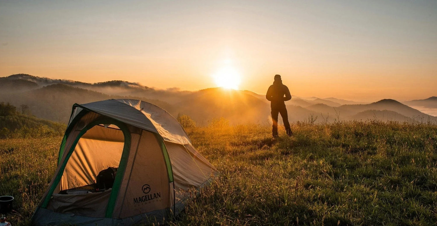 Camping tent at sunrise with hiker silhouetted against misty mountains, ideal for outdoor adventures.
