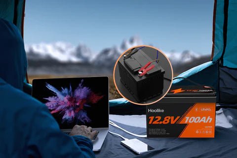 "Hoolike 12.8V 100Ah battery powering devices in an outdoor camping setup."