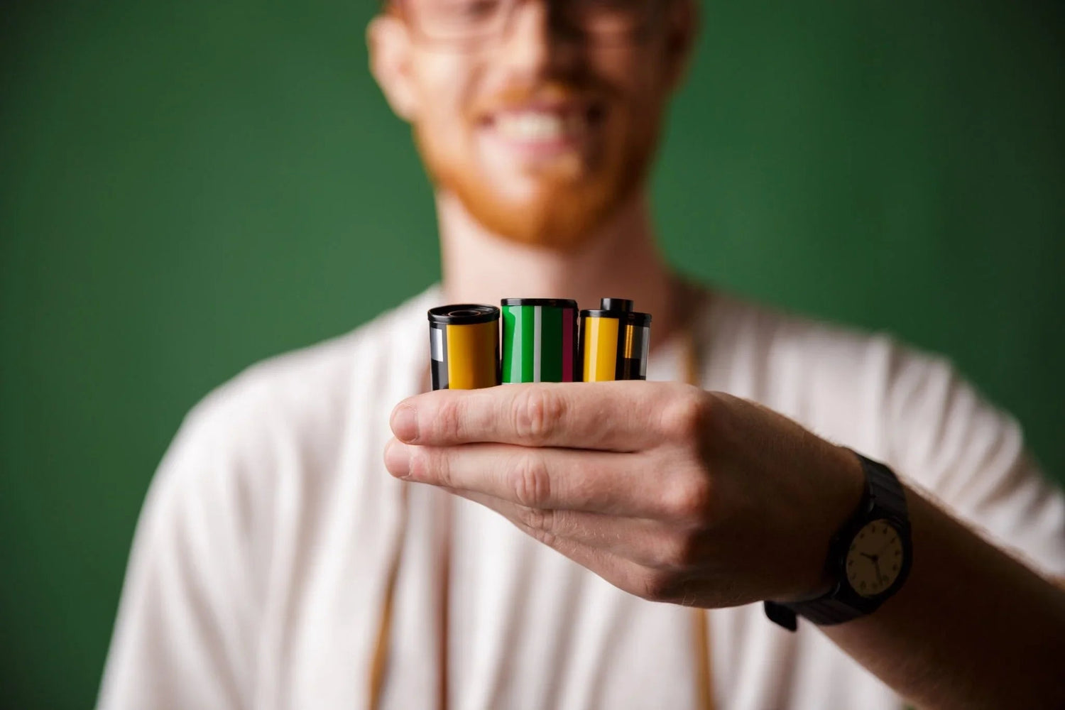 Man holding colorful cylindrical batteries with green background